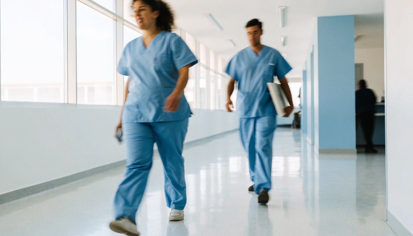 Zwei Pflegekräfte gehen durch einen hellen Klinikgang